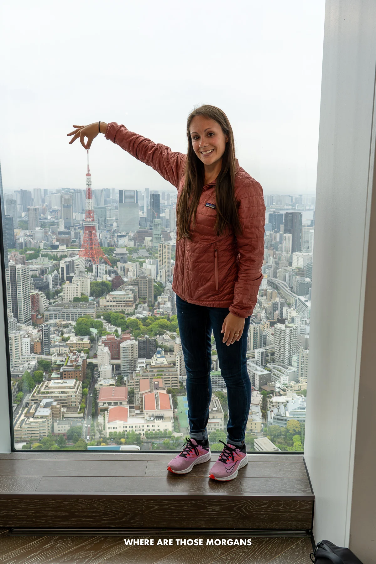 Kristen from Where Are Those Morgans pinching the Tokyo Tower through a window inside a nearby observation deck in Roppongi Hills