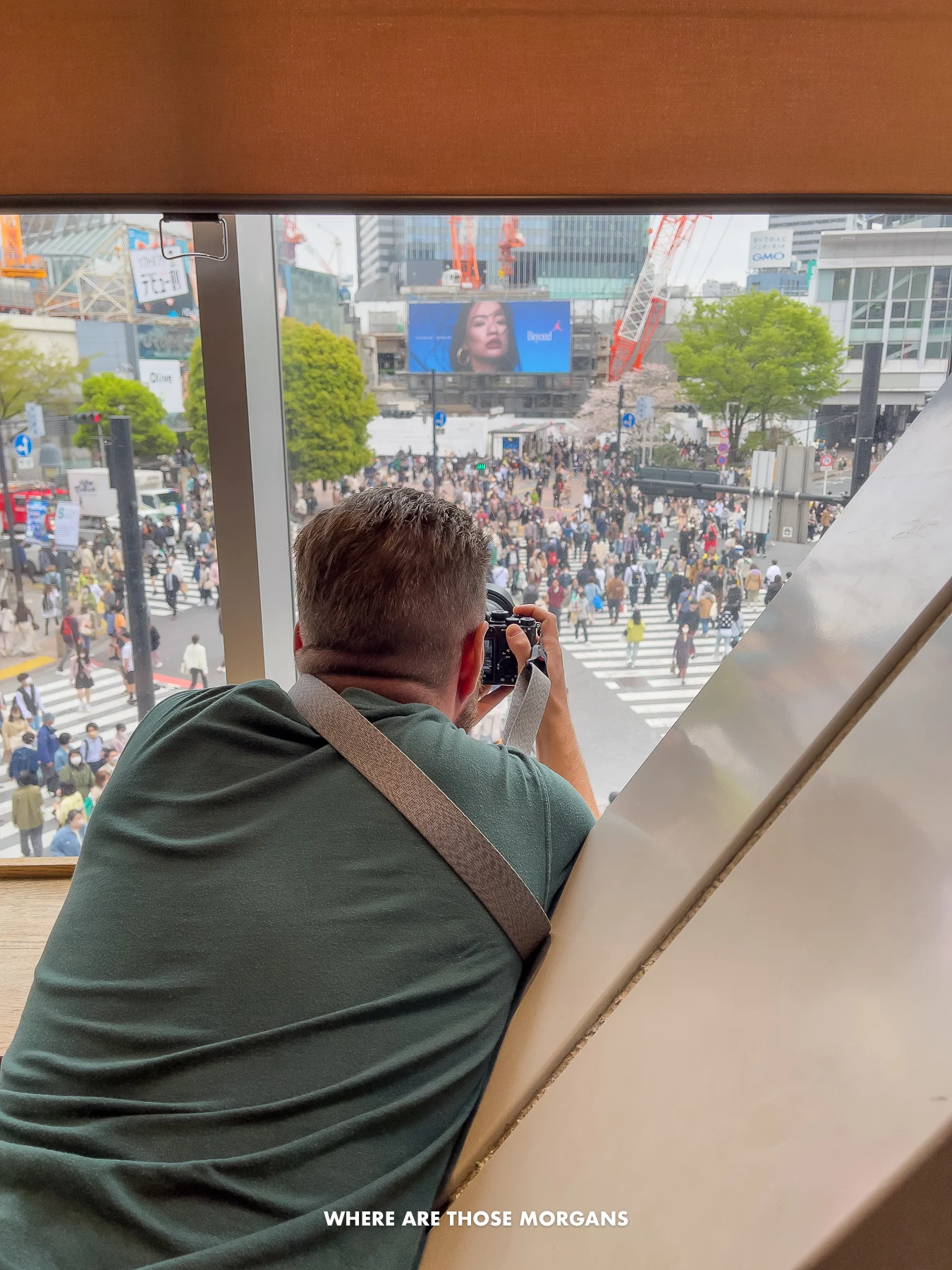 Mark from Where Are Those Morgans leaning over a table and taking a photo with a camera through a window