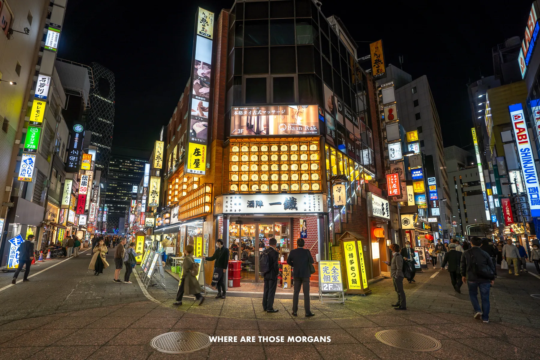 Shinjuku streets lit up at night with tourists and locals walking around under the neon lit buildings