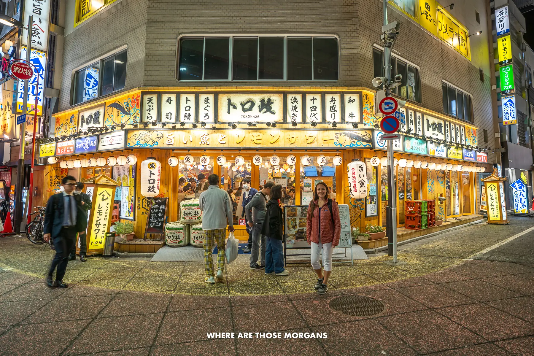 Kristen from Where Are Those Morgans standing outside a lit up restaurant on a street corner with other people lining up to get in at night