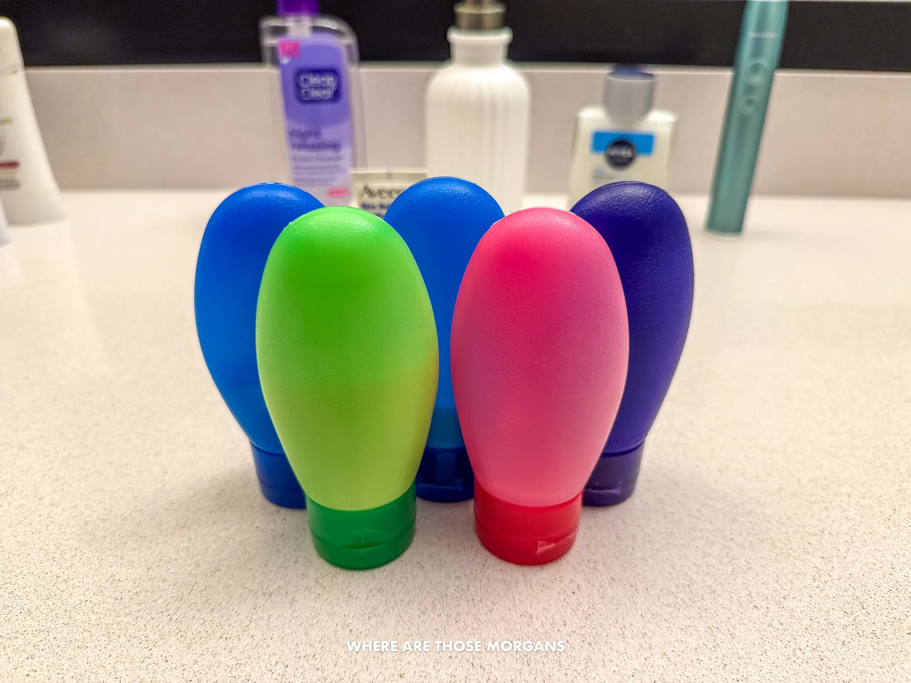 Five small colorful travel sized bottles for toiletries