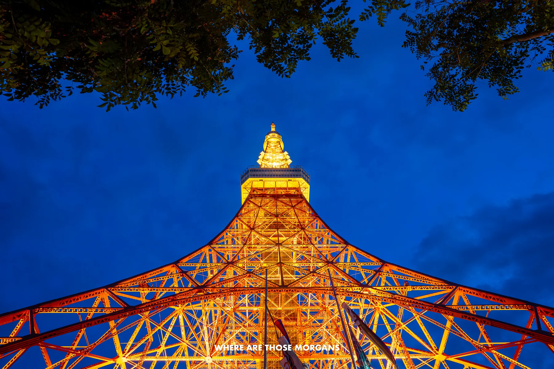 Looking up at the Tokyo Tower from below lit up orange at dusk