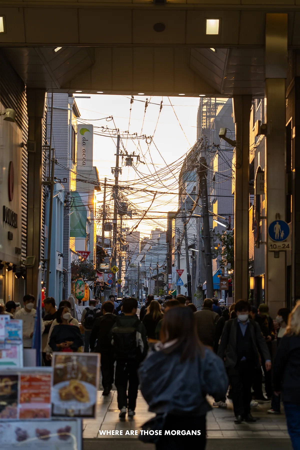 Locals and tourists walking through a shopping center and street with lots of power lines exposed at sunset