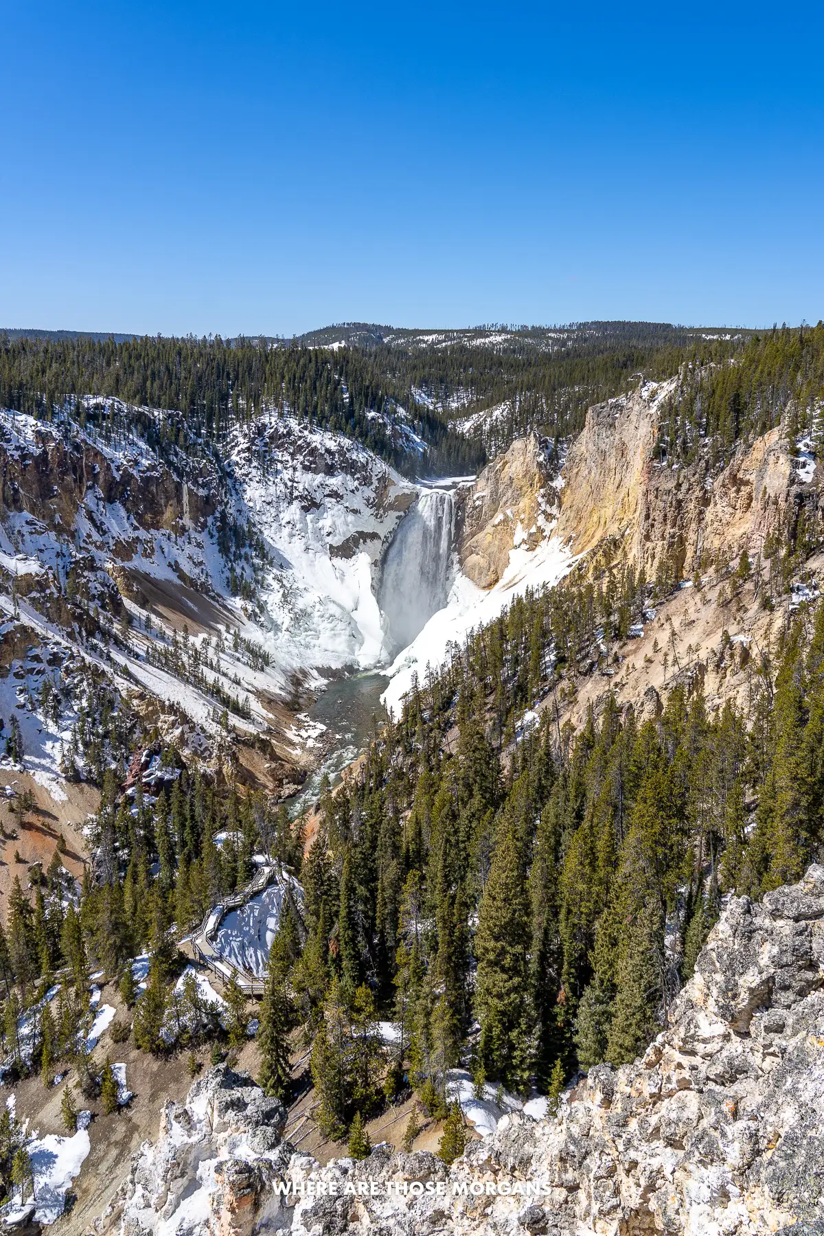 Looking up a long and deep canyon at a distant waterfall under a clear blue sky