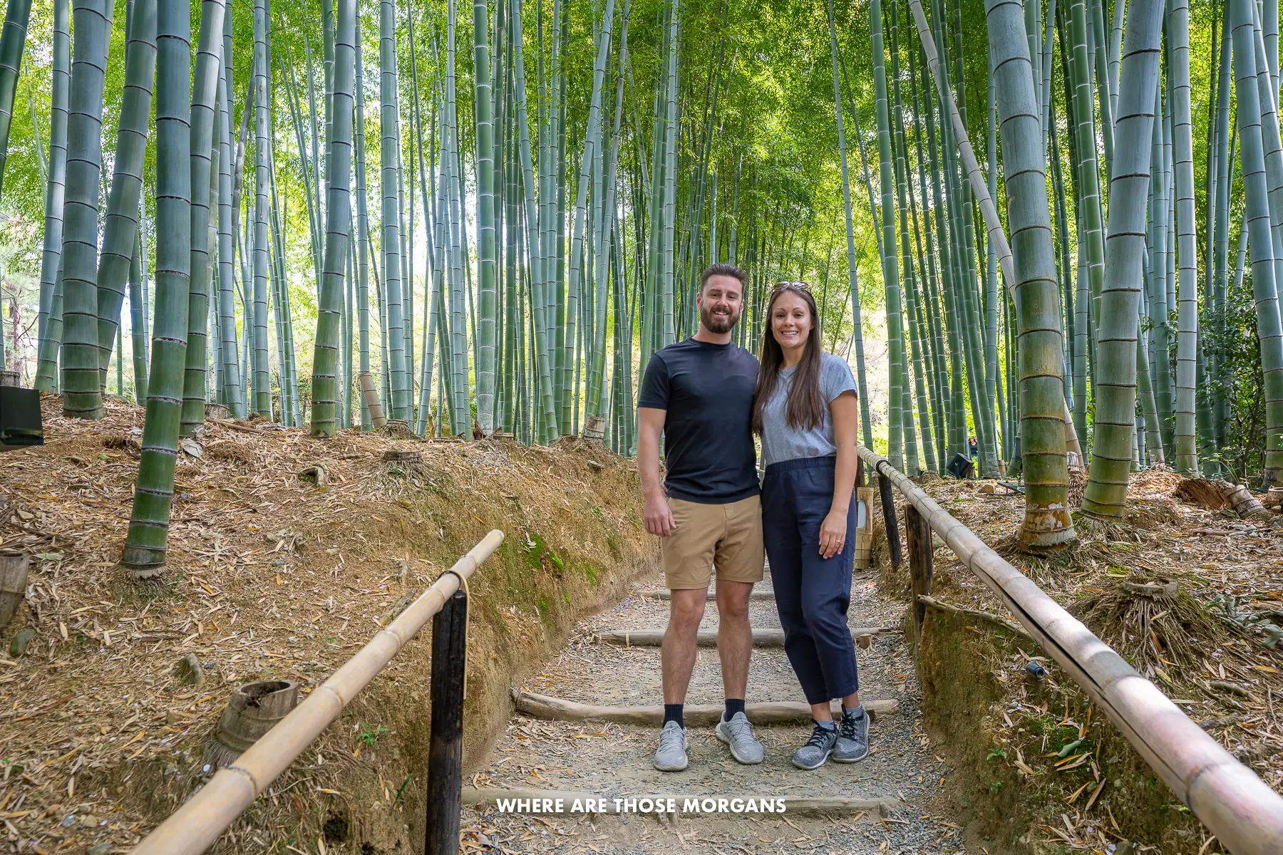 Mark and Kristen from Where Are Those Morgans standing on a narrow sloped footpath inside a bamboo forest in Kyoto, Japan