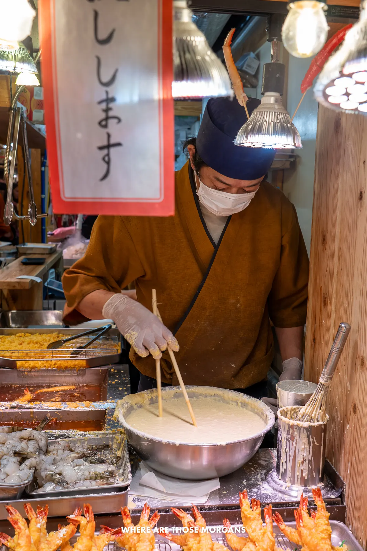 Worker at a food stall in a Japanese market stirring a batter mix