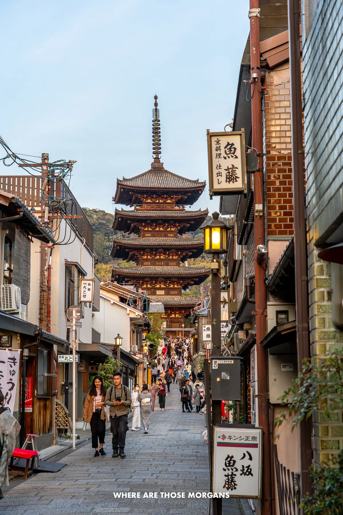 Five story pagoda at the end of a narrow street in southern Higashiyama with tourists and locals walking along the street
