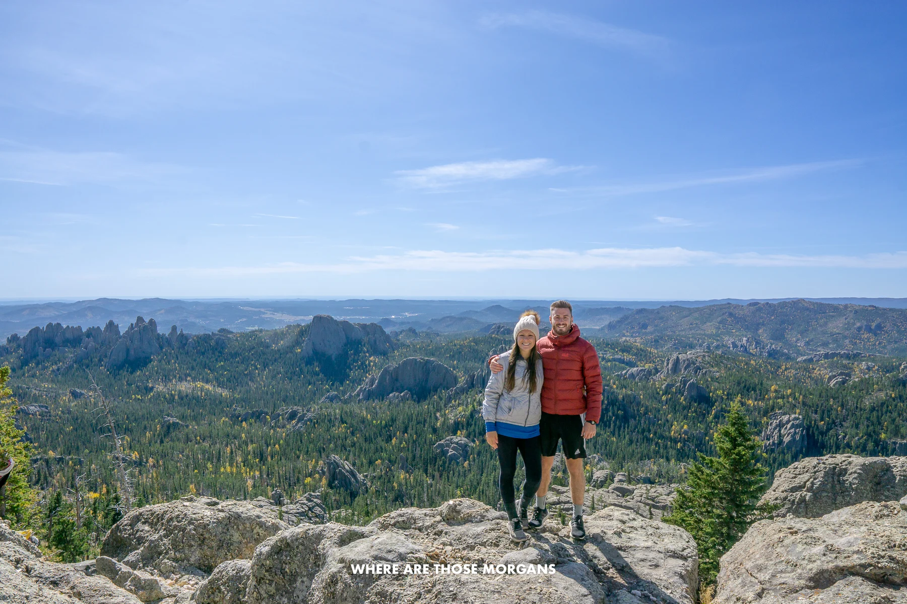 Mark and Kristen from Where Are Those Morgans standing together at the summit of Black Elk Peak with far reaching views over a wide open landscape