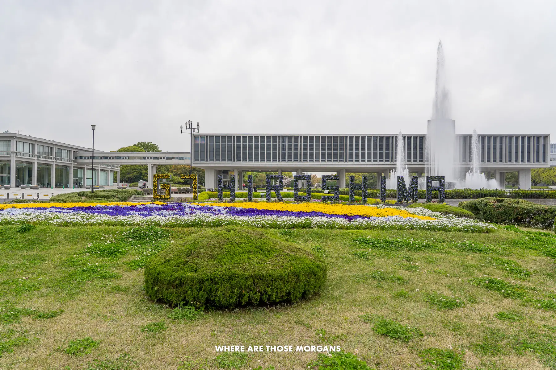 Looking at Hiroshima Peace Museum with a garden, fountain, and building behind the word G7 Hiroshima spelled out as a sign