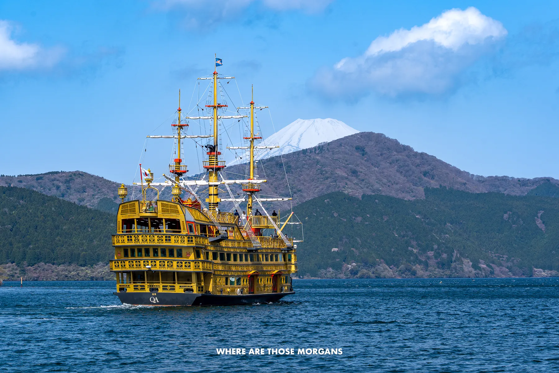 Yellow and black Pirate Ship crossing Lake Ashi with hills and Mt Fuji in the background in Hakone, Japan