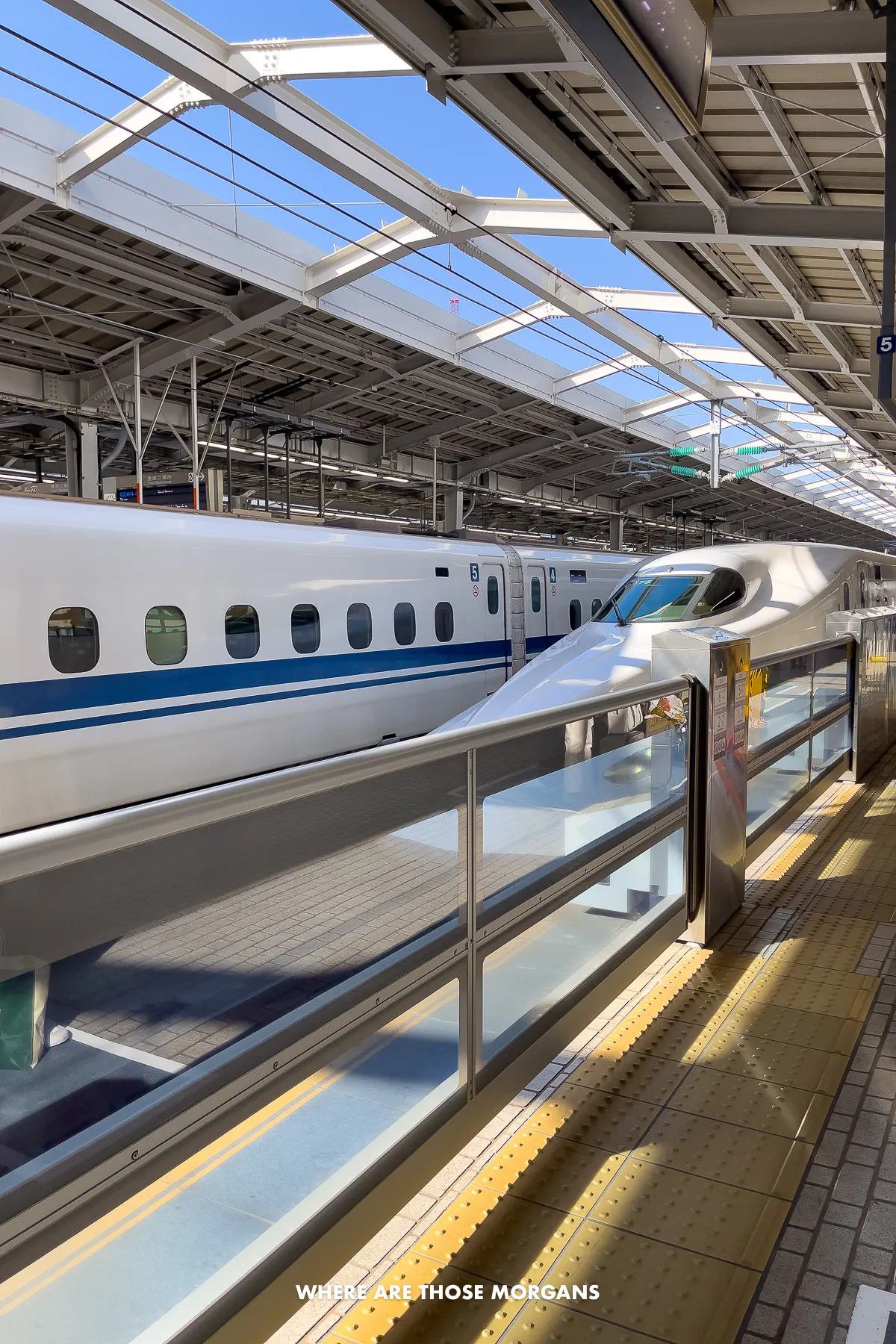 Two bullet trains at Shin-Osaka station on a clear sunny day