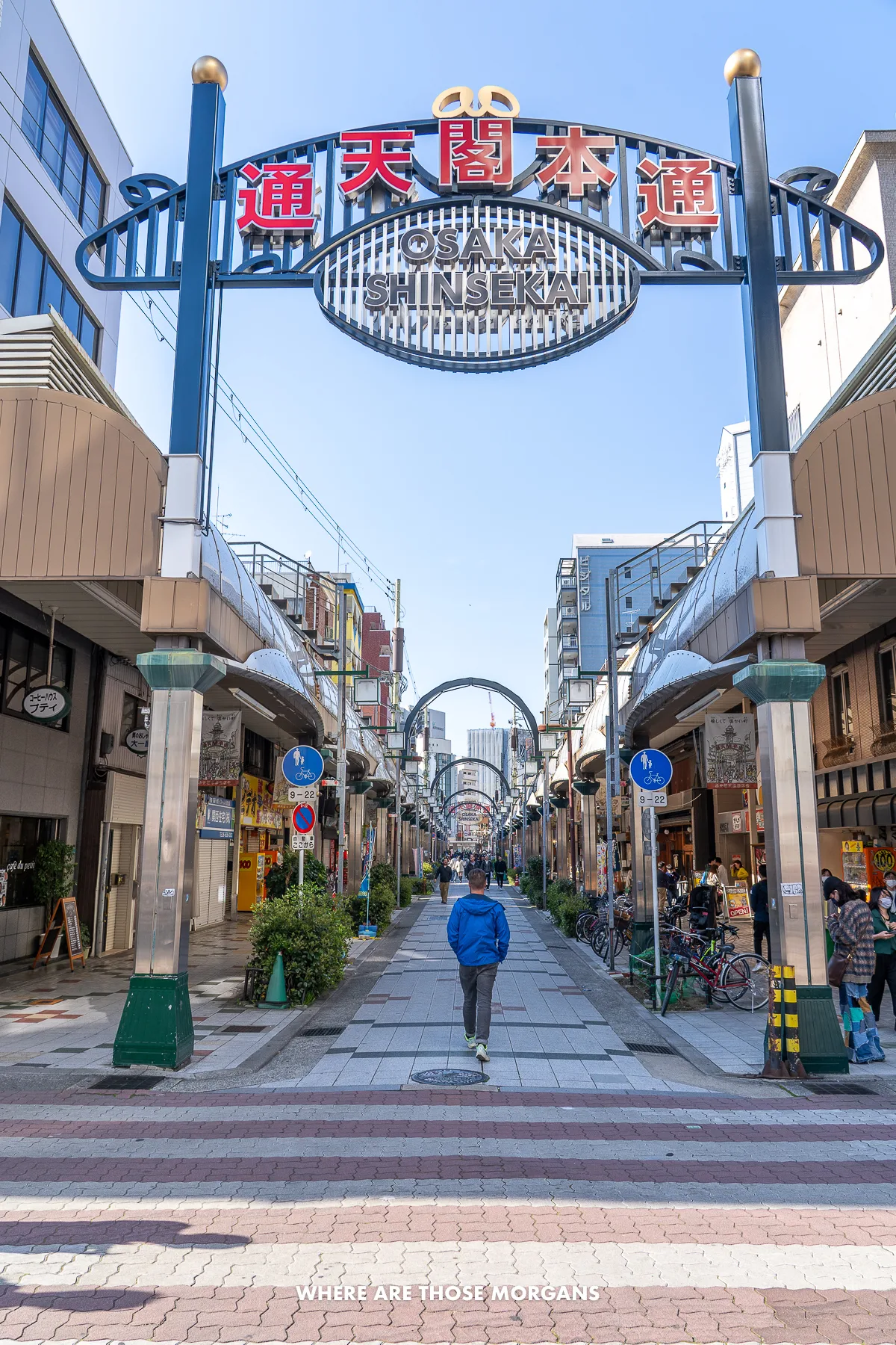 Mark from Where Are Those Morgans entering Shinsekai neighborhood in Osaka through a gate into a narrow street lined with shops and restaurants