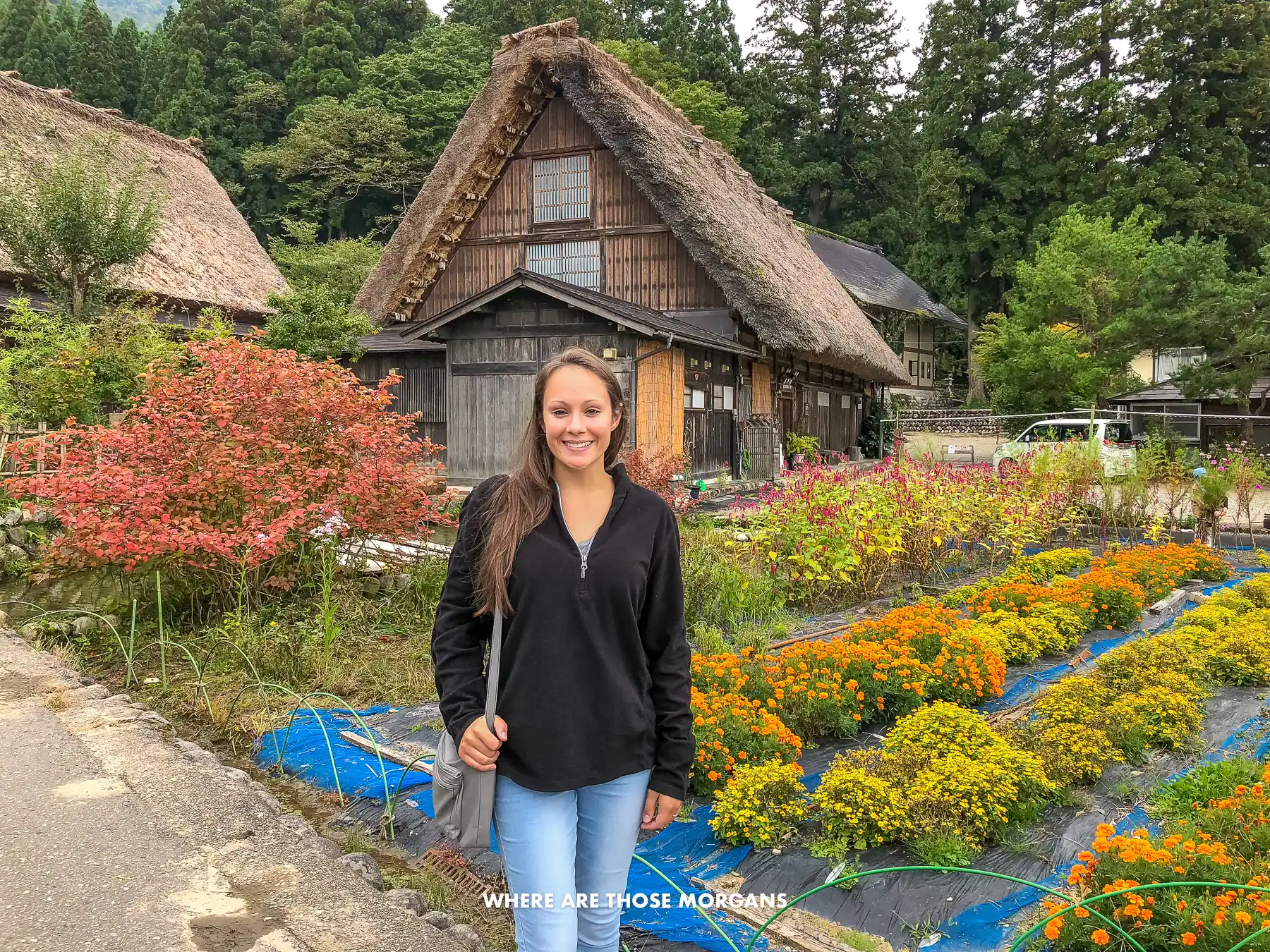 Kristen from Where Are Those Morgans standing in front of a cottage with steep thatched roof and garden in Shirakawa-go Japan