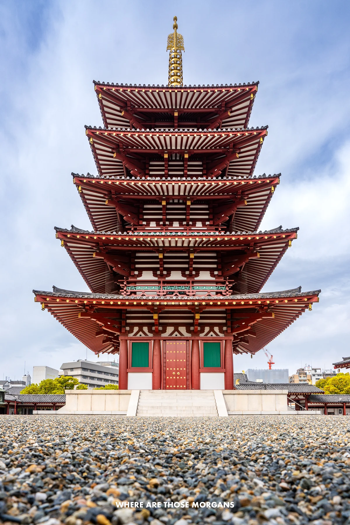 Striking five-story pagoda bursting into the sky from behind a gravel courtyard in Osaka