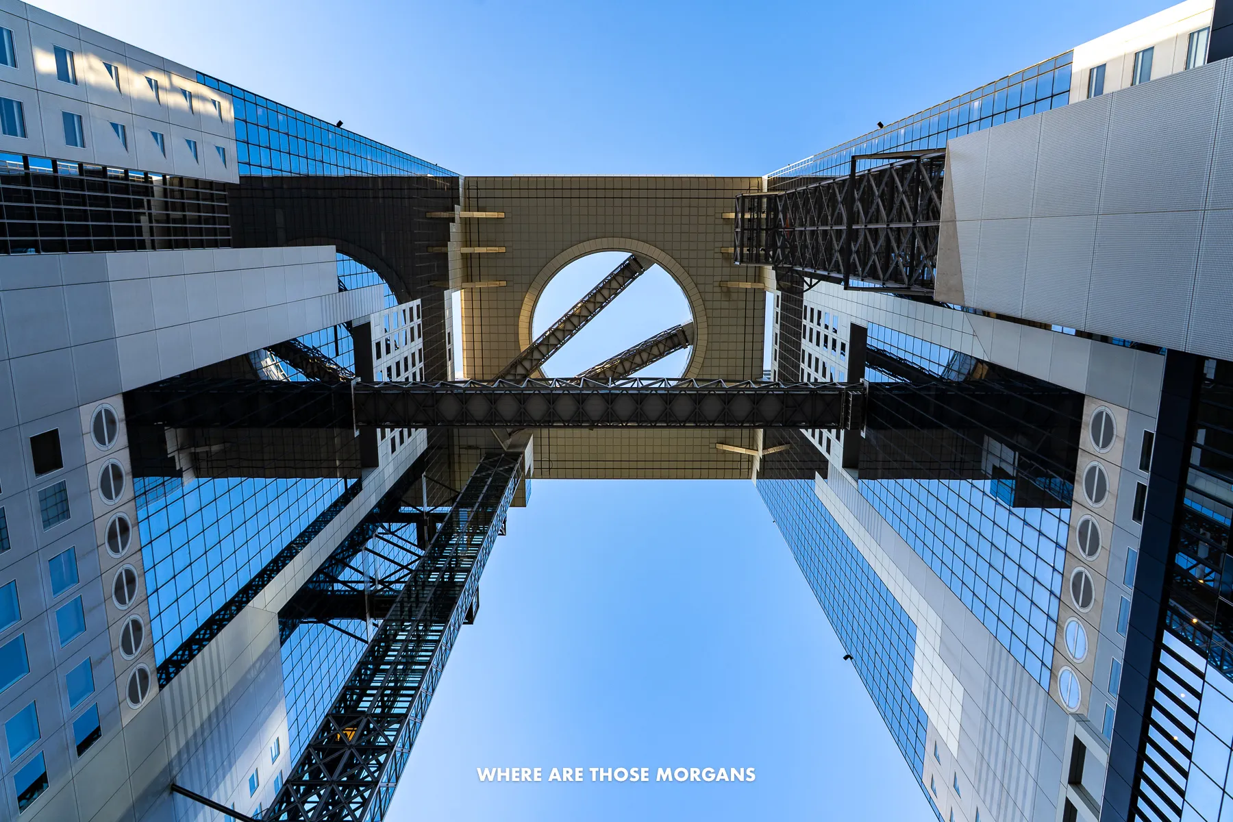 Looking up at Umeda Sky Building from directly below with escalators crossing between two towers and a circular rooftop observatory