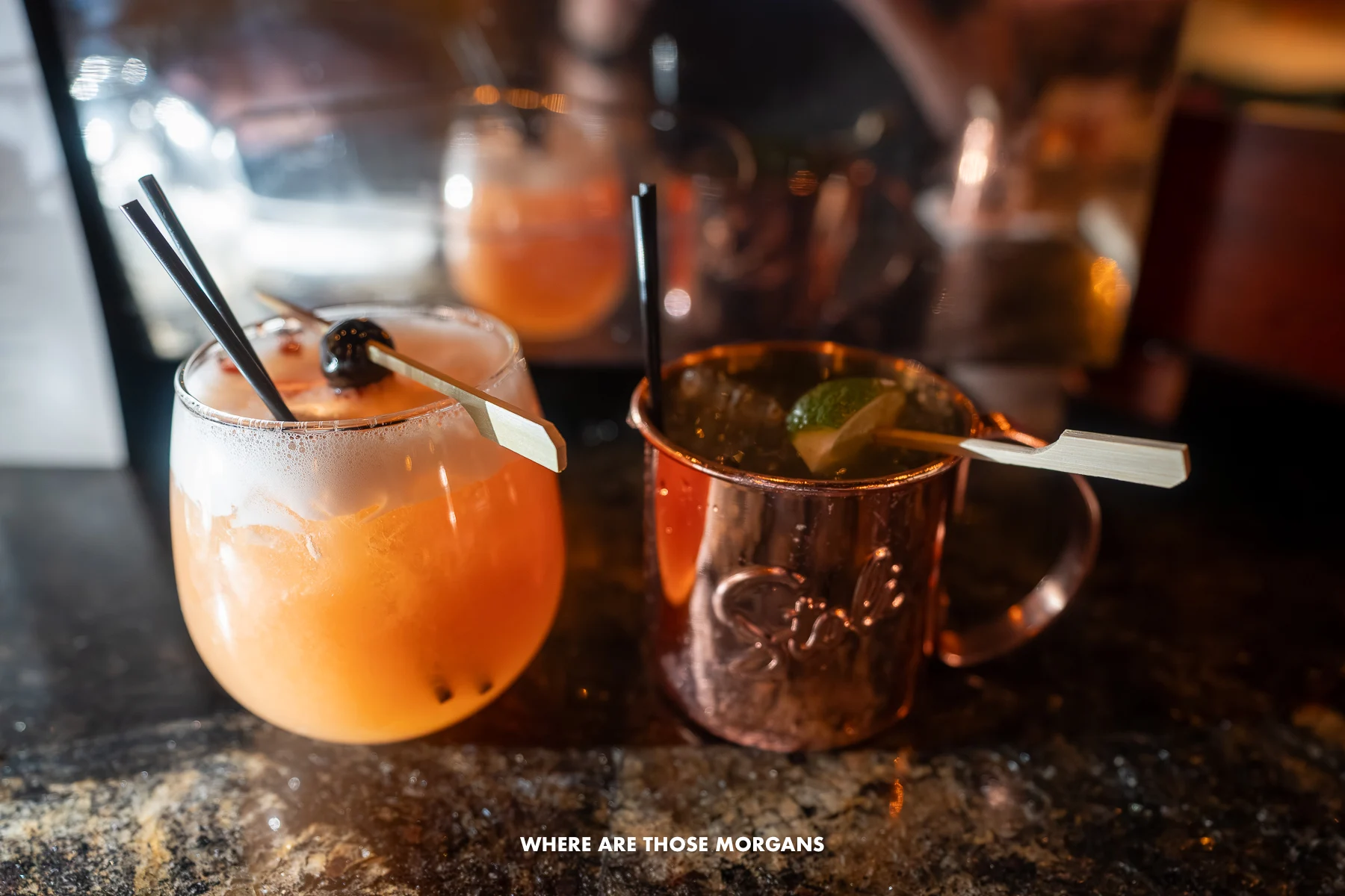 Two fancy cocktails on a marble surface in a bar