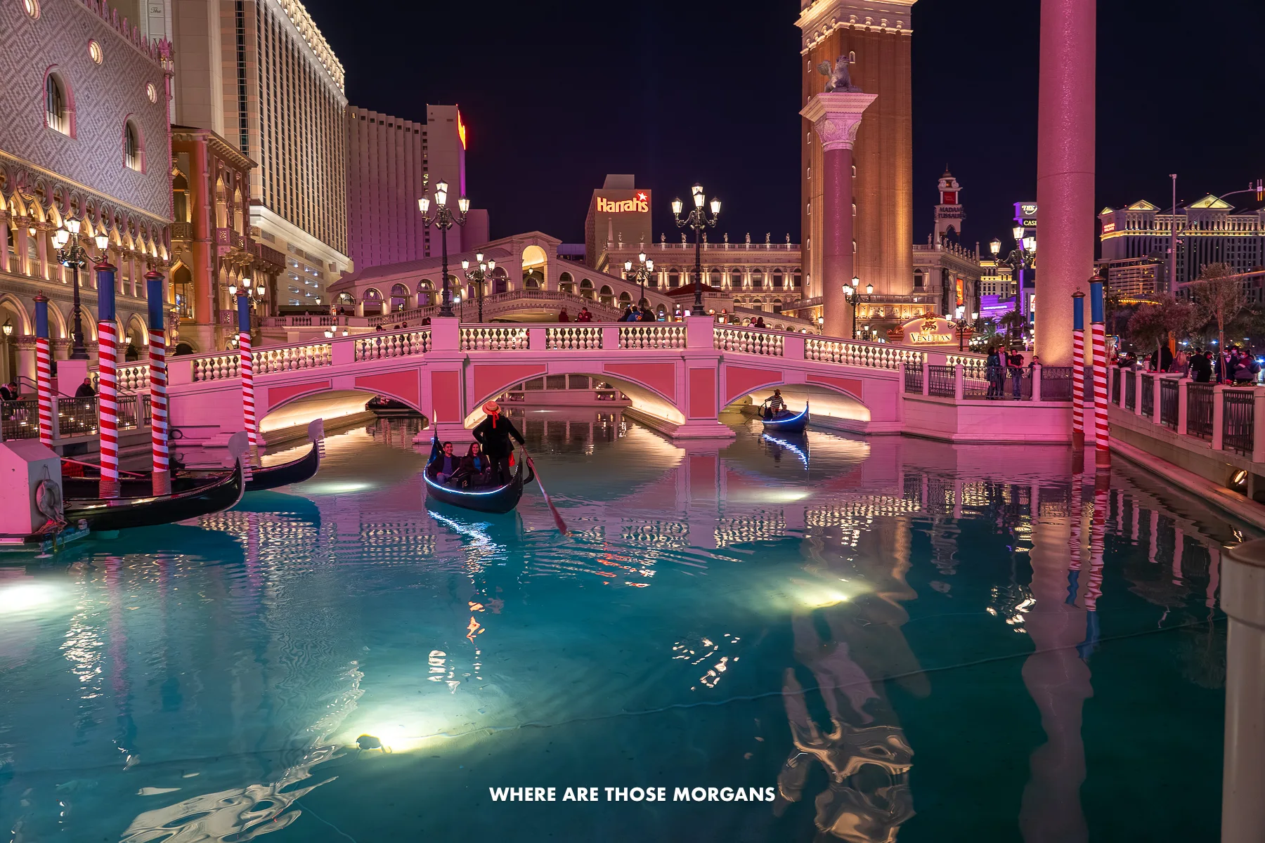 The outdoor canals of The Venetian in Las Vegas with a few gondolas floating on illuminated water