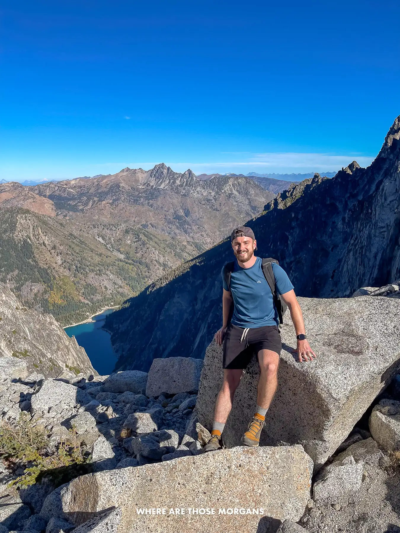 Mark from Where Are Those Morgans sat on a boulder at the top of Aasgard Pass under a clear blue sky