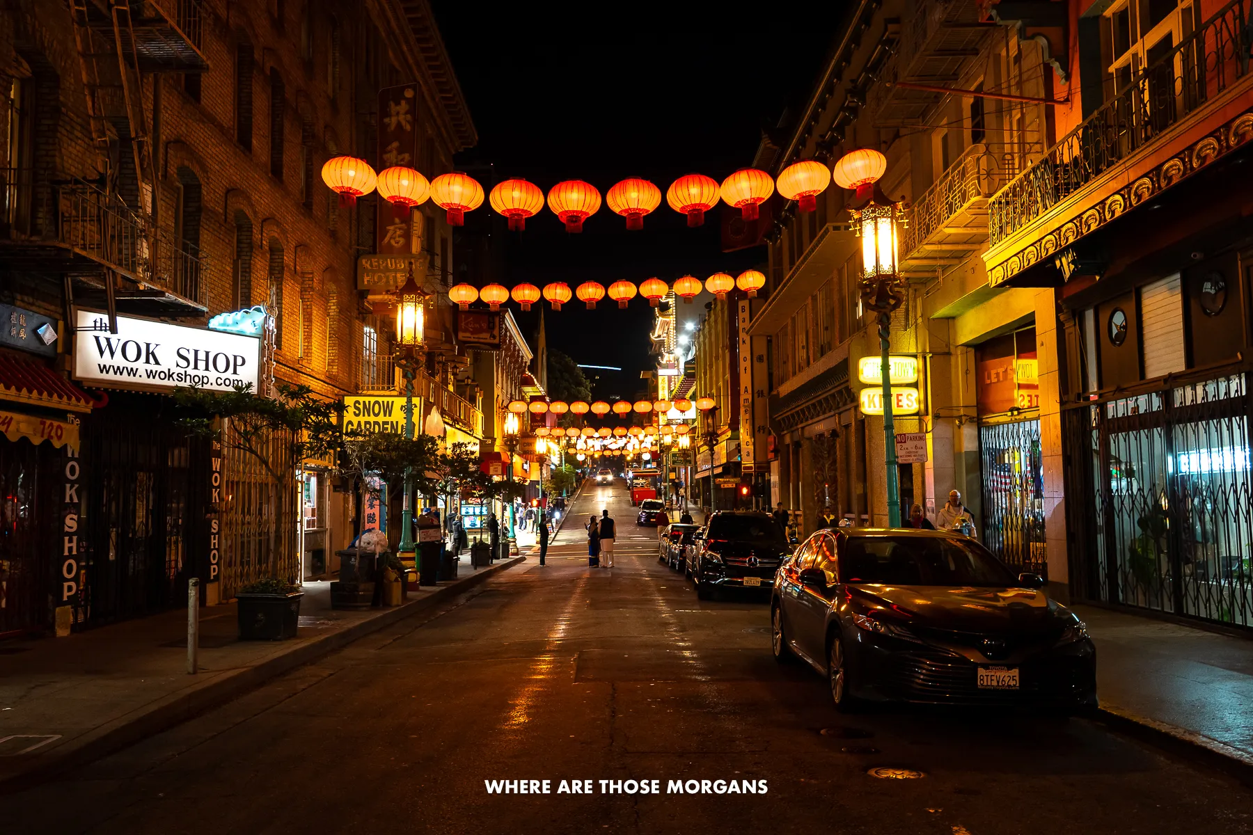 Street in Chinatown SF with lanterns glowing red above parked cars