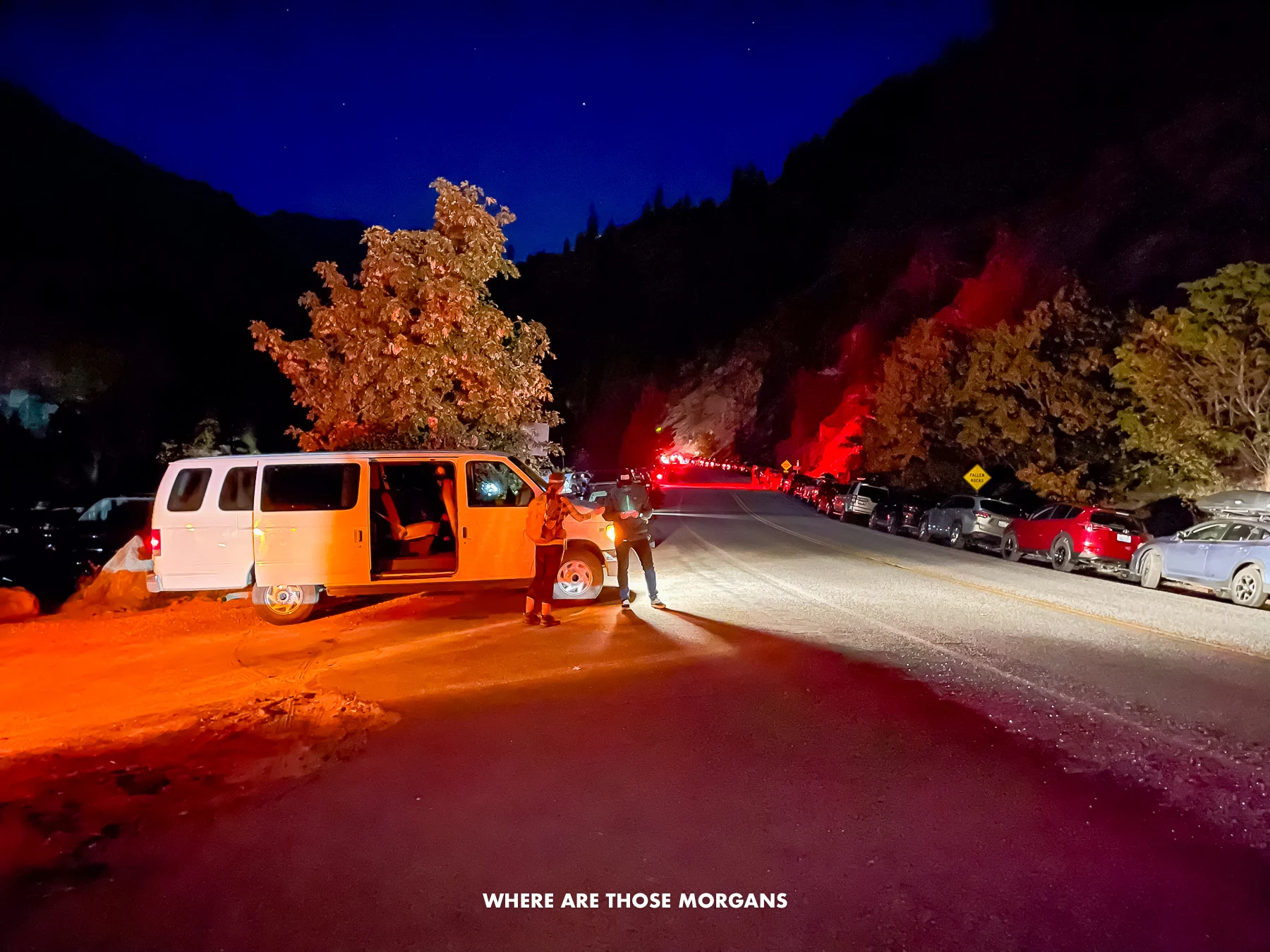 Snow Lakes Trailhead in Washington in the dark with cars parked on the roadside and a white minivan picking up hikers