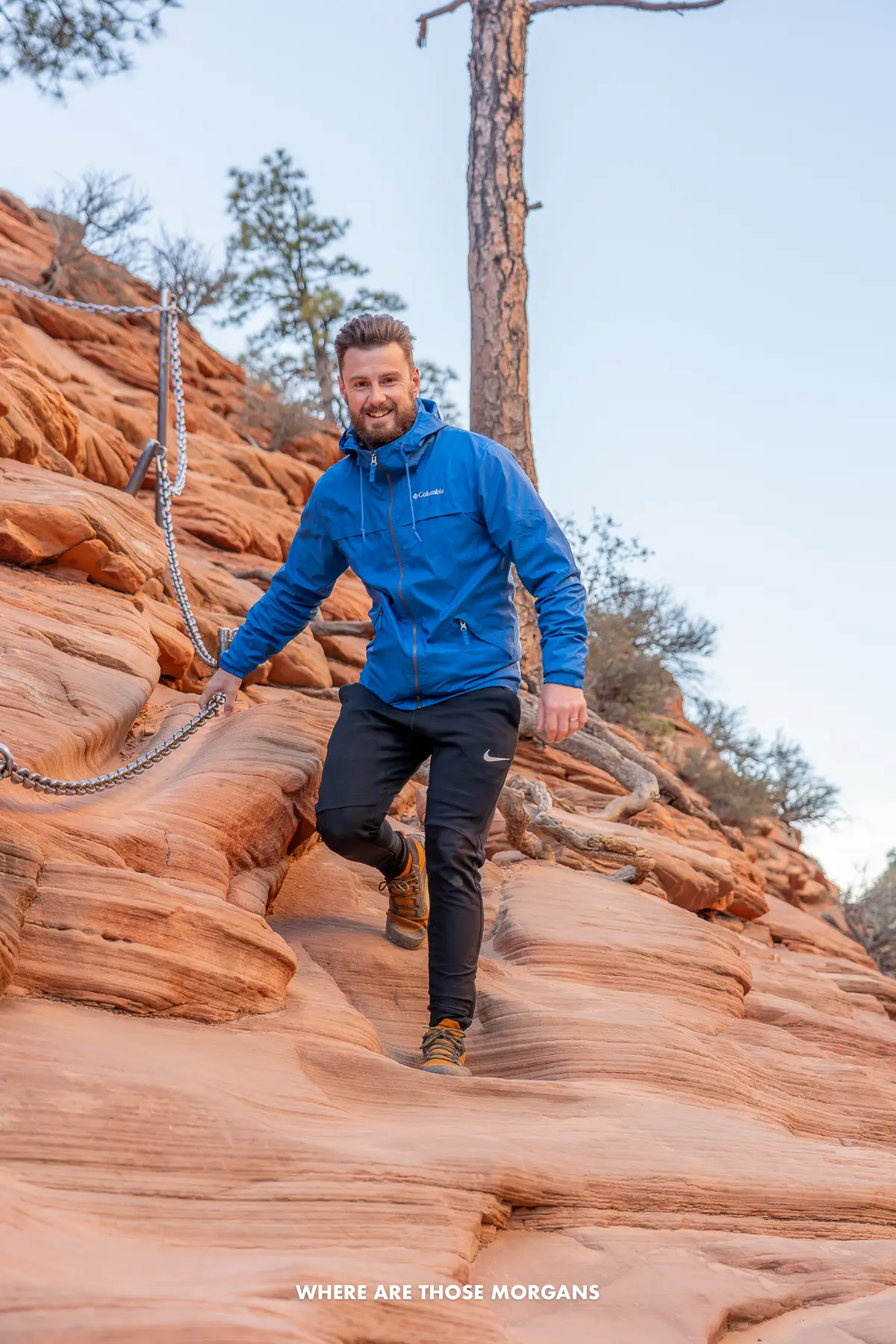 Mark from Where Are Those Morgans hiking down red rocks holding a metal chain in Utah on a cold morning