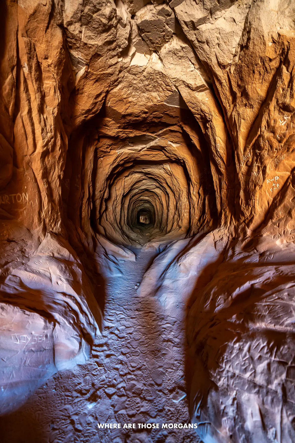 The inside of Belly of the Dragon near Kanab in Utah, a long water drainage tunnel that has eroded orange and purple rocks appearing like the inside of a dragon