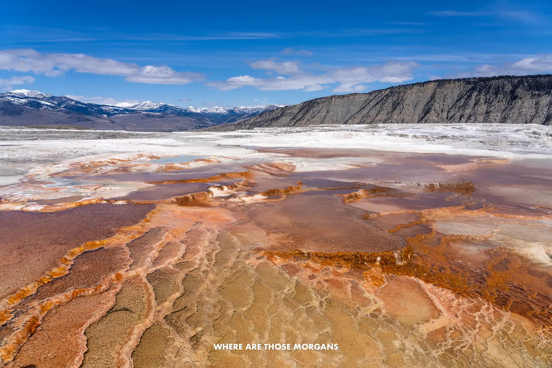 Flat travertine terrace with vibrant colors leading to rolling hills in a wide open rocky landscape in Wyoming
