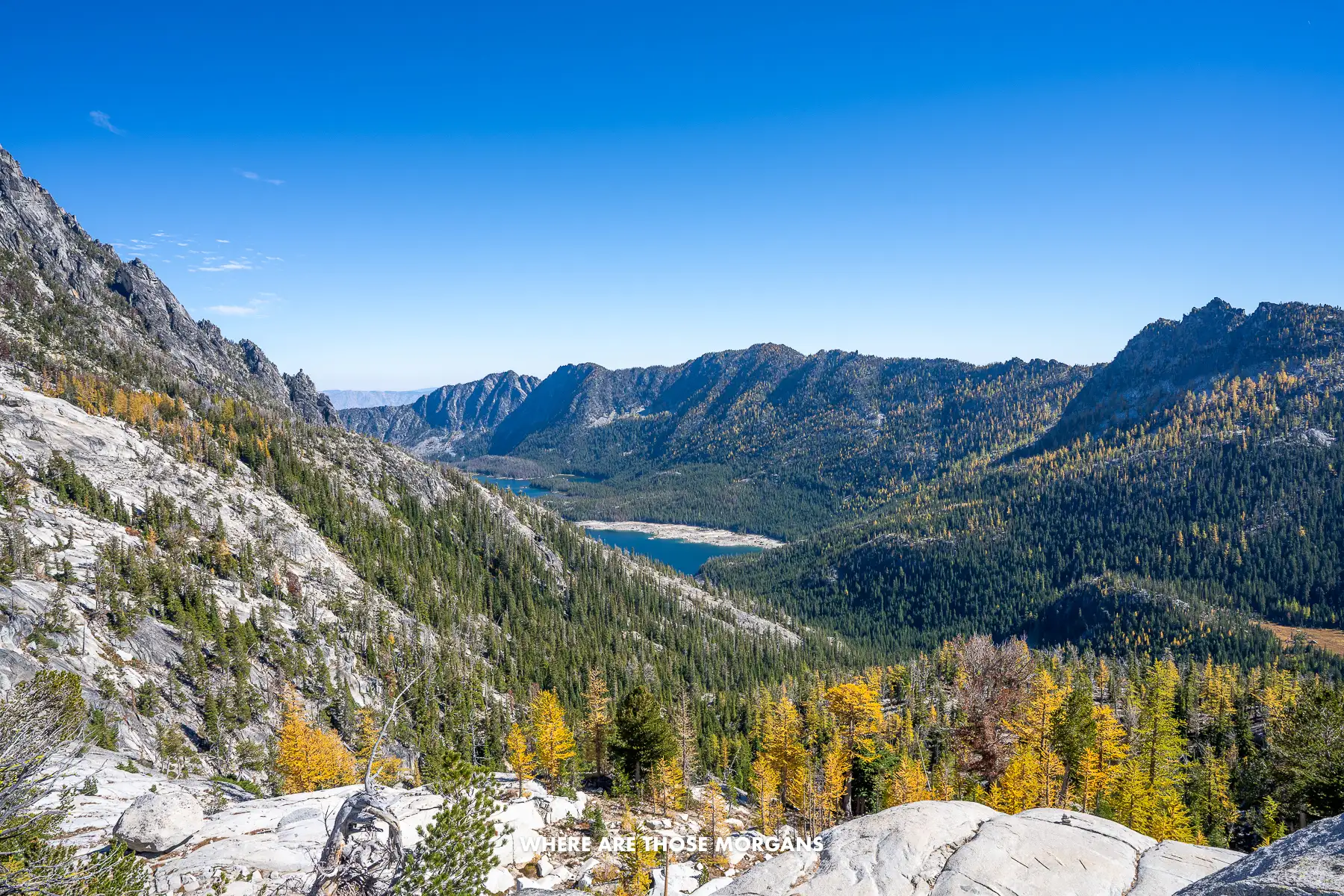 View of a small blue lake in a deep valley surrounded by trees and mountains in Washington State