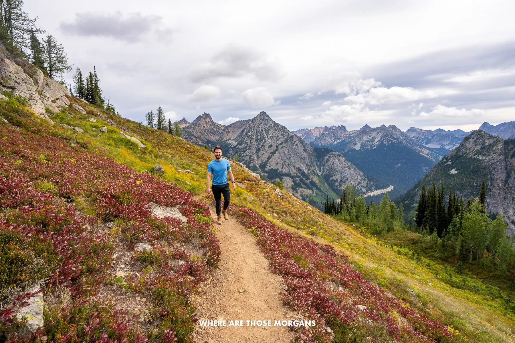 Mark from Where Are Those Morgans hiking Maple Pass Loop in Washington with snow capped mountain views behind