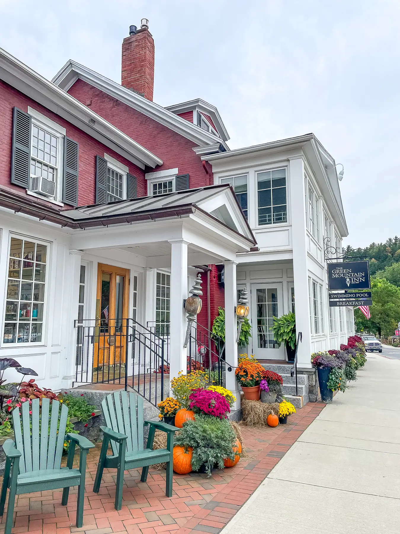 Photo of the Green Mountain Inn hotel in Stowe VT from the outside with chairs and pumpkins near the entrance