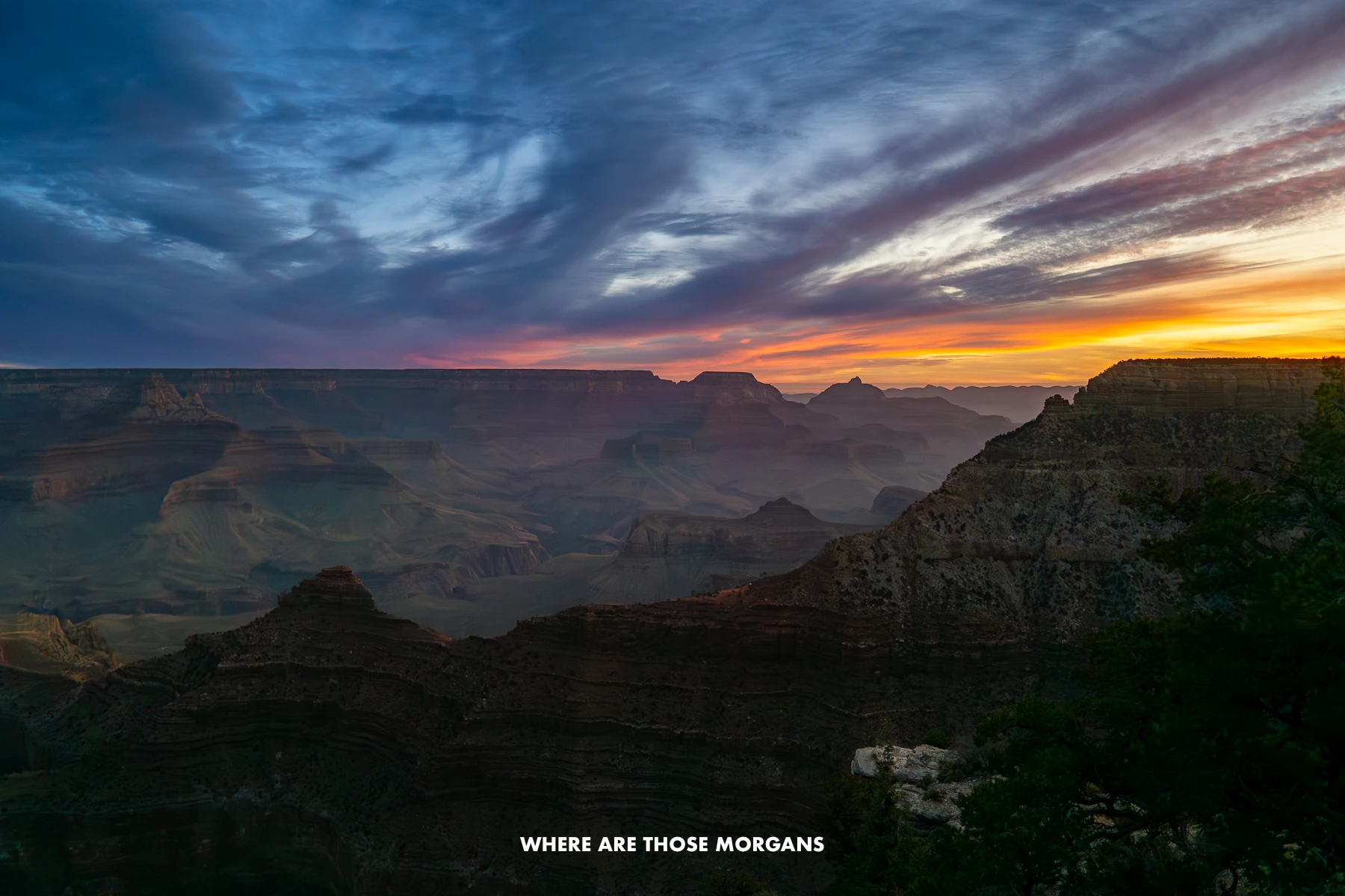 View of the Grand Canyon at dawn with shadows in the canyon and vibrant colors above in the clouds