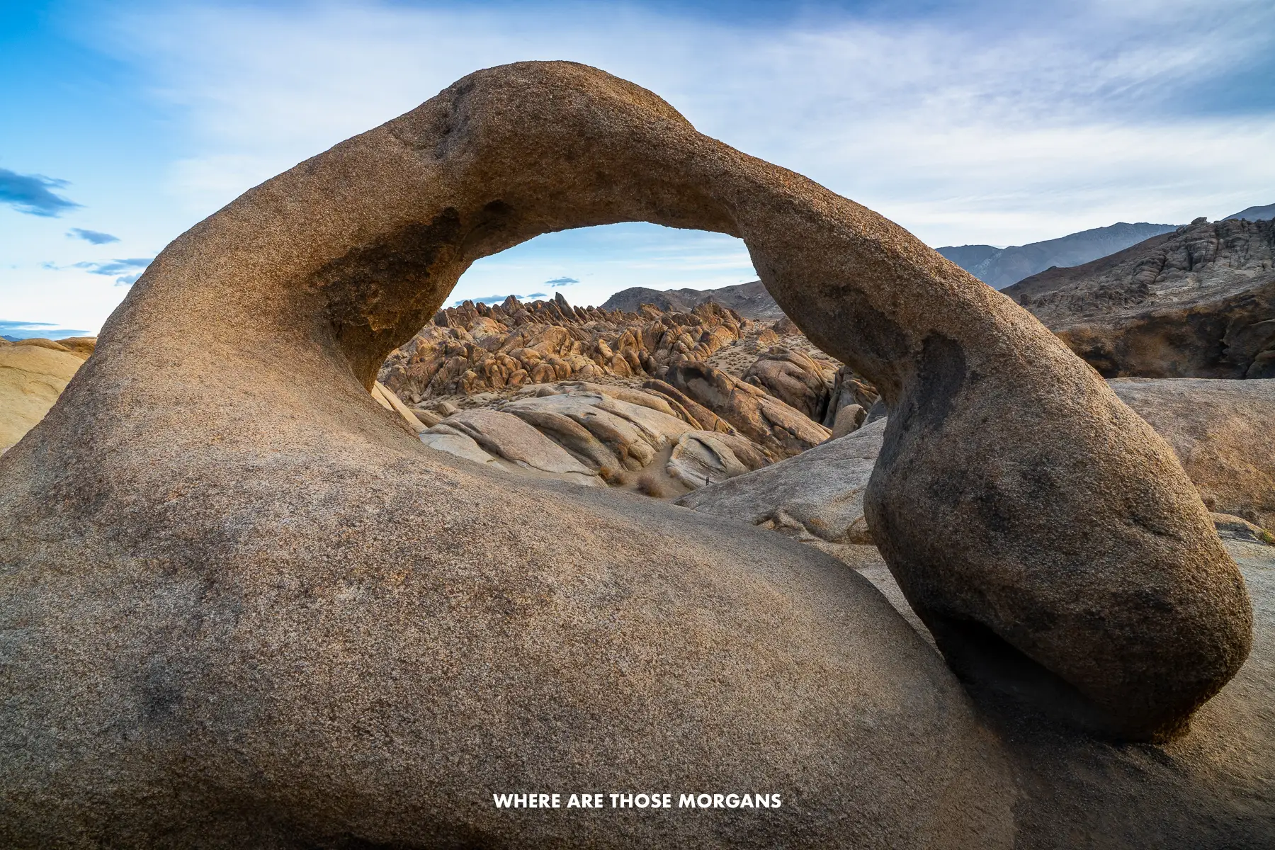 The unusually shaped Mobius Arch at dawn with a rocky landscape seen through the "window" of the arch