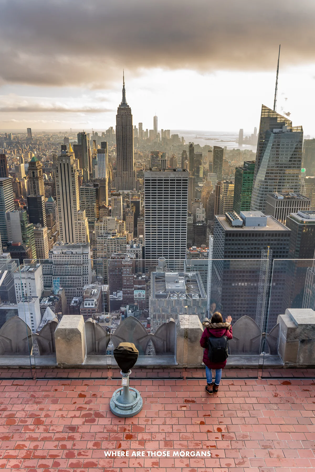 Kristen from Where Are Those Morgans standing against a glass window looking out at the NYC skyline at sunset