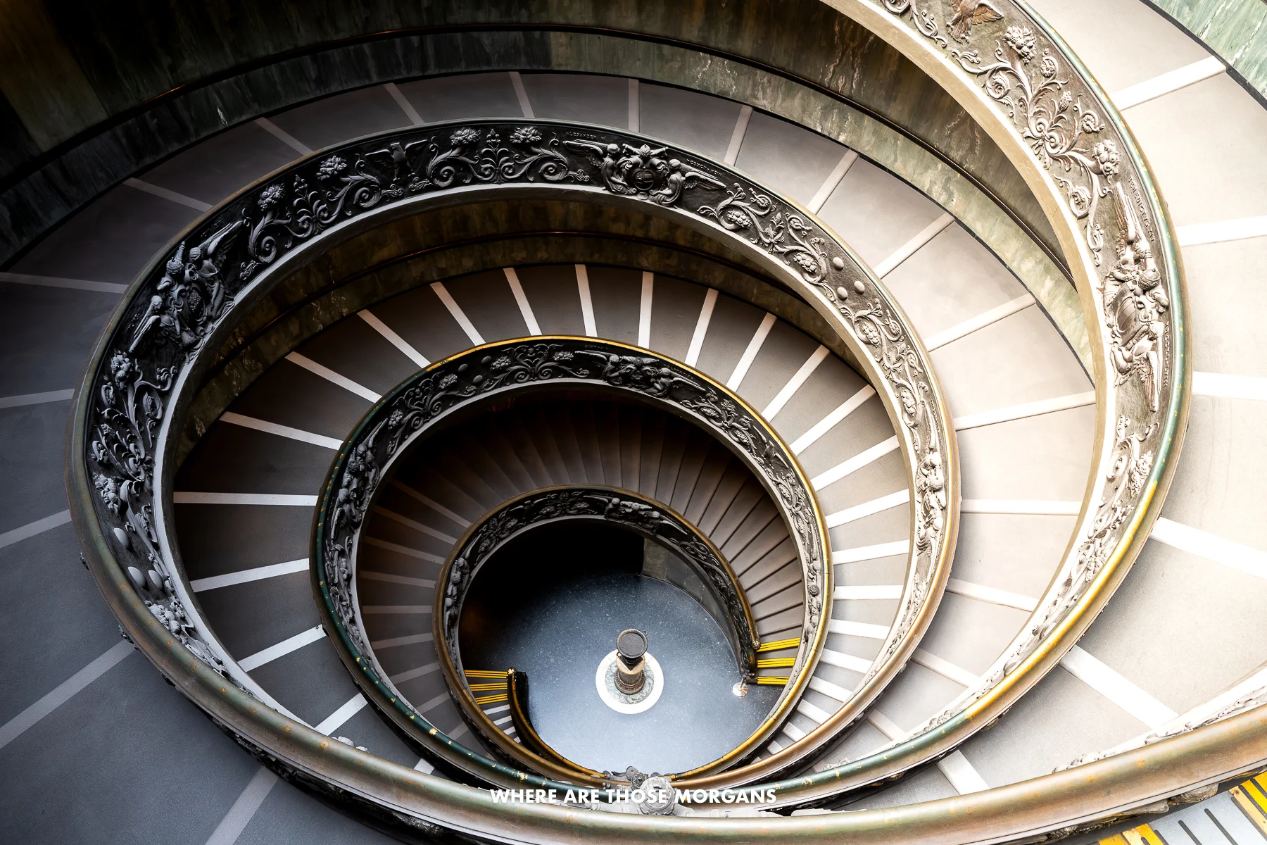 Photo looking down the spiraling Bramante Staircase in the Vatican Museum half covered in light and half in shadow