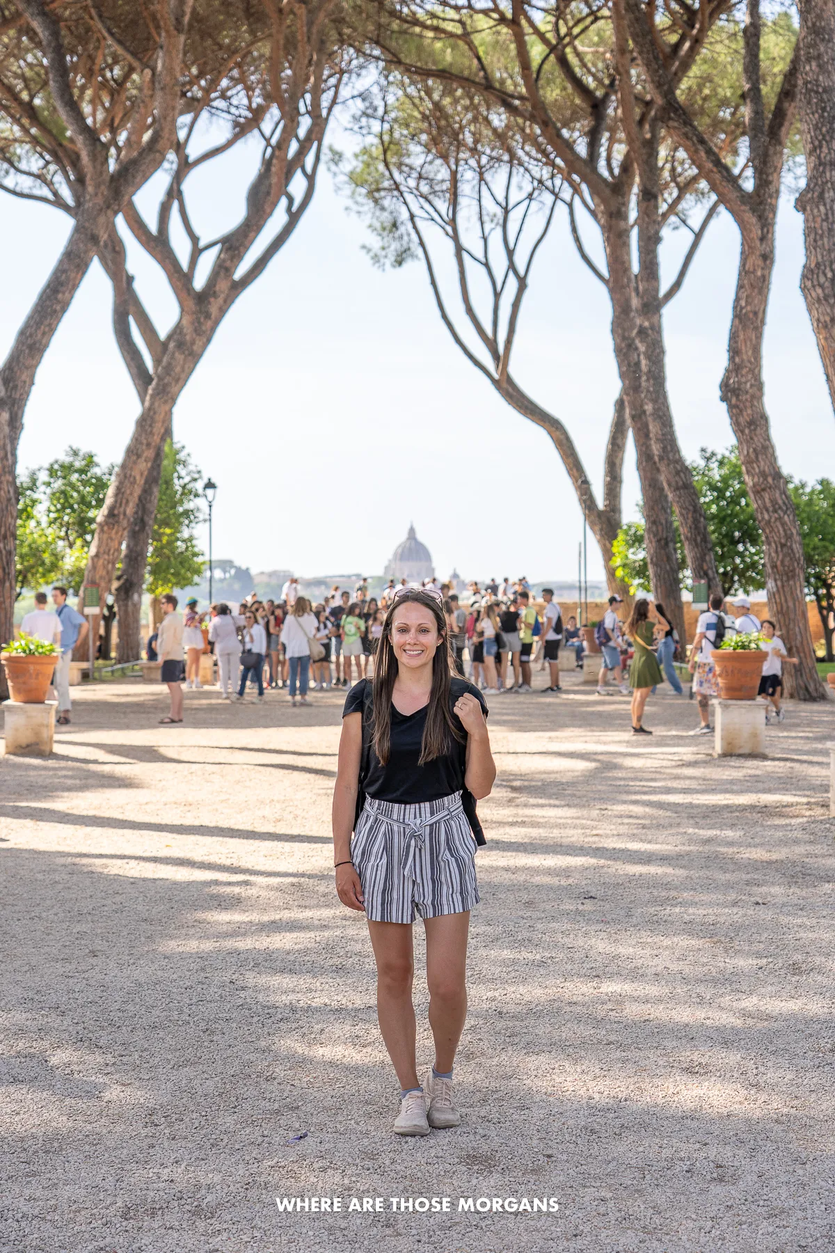 Kristen from Where Are Those Morgans standing on a gravel path with trees to either side and a crowd of people at a viewing terrace behind