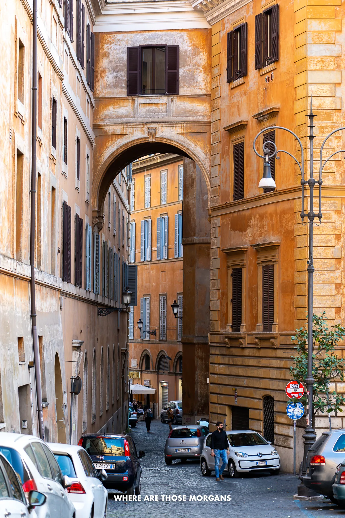 Narrow road with cars parked leading in between tall buildings in Italy