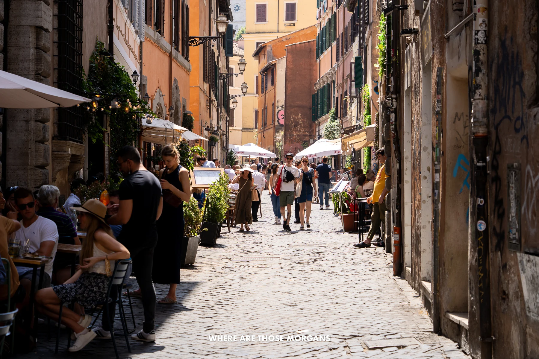 Cobbled street in Trastevere neighborhood of Rome filled with diners and tourists walking