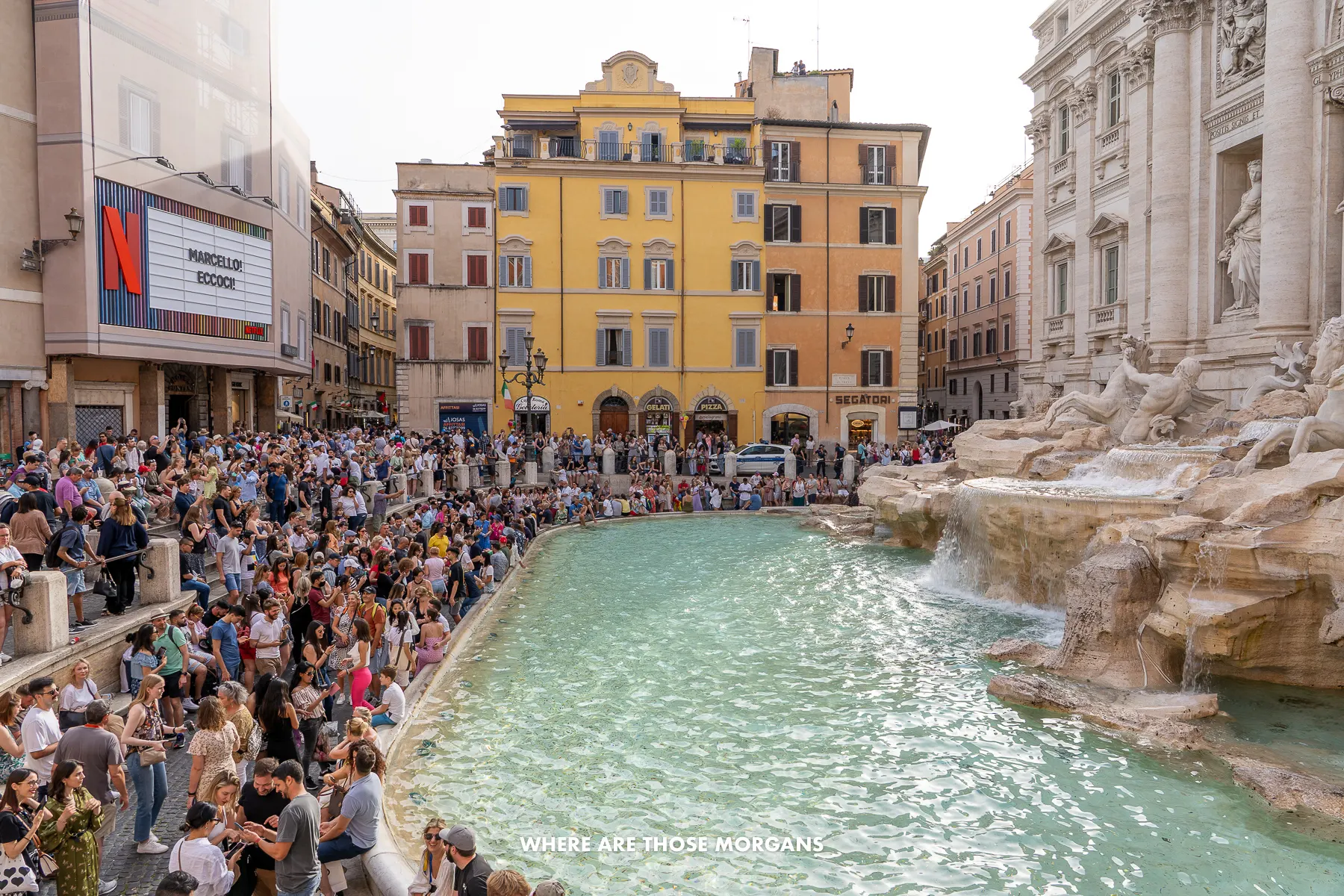 Photo of the Trevi Fountain completely surrounded by tourists in the late afternoon