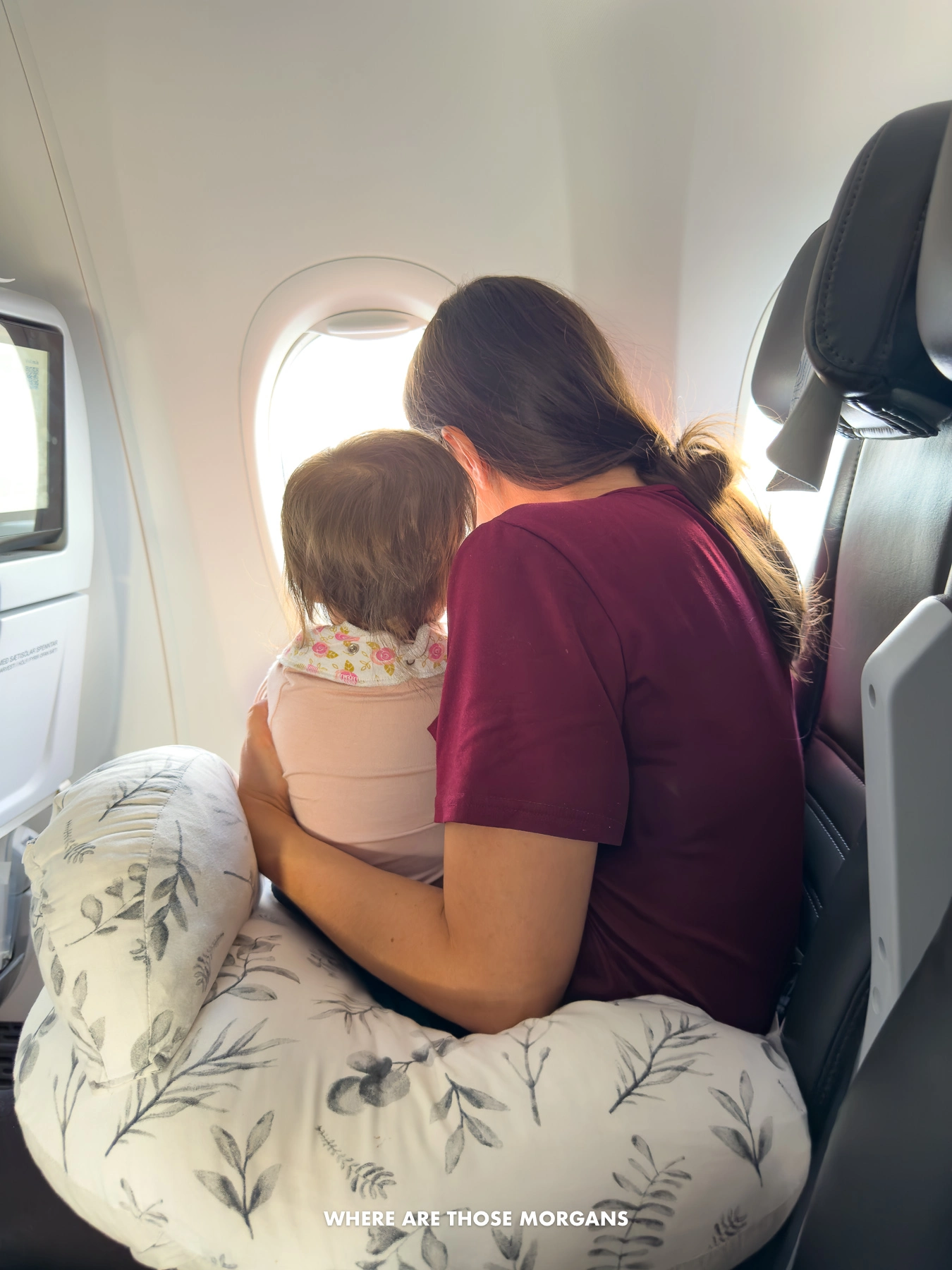 Kristen from Where Are Those Morgans holding her daughter in front of a plane window before take off