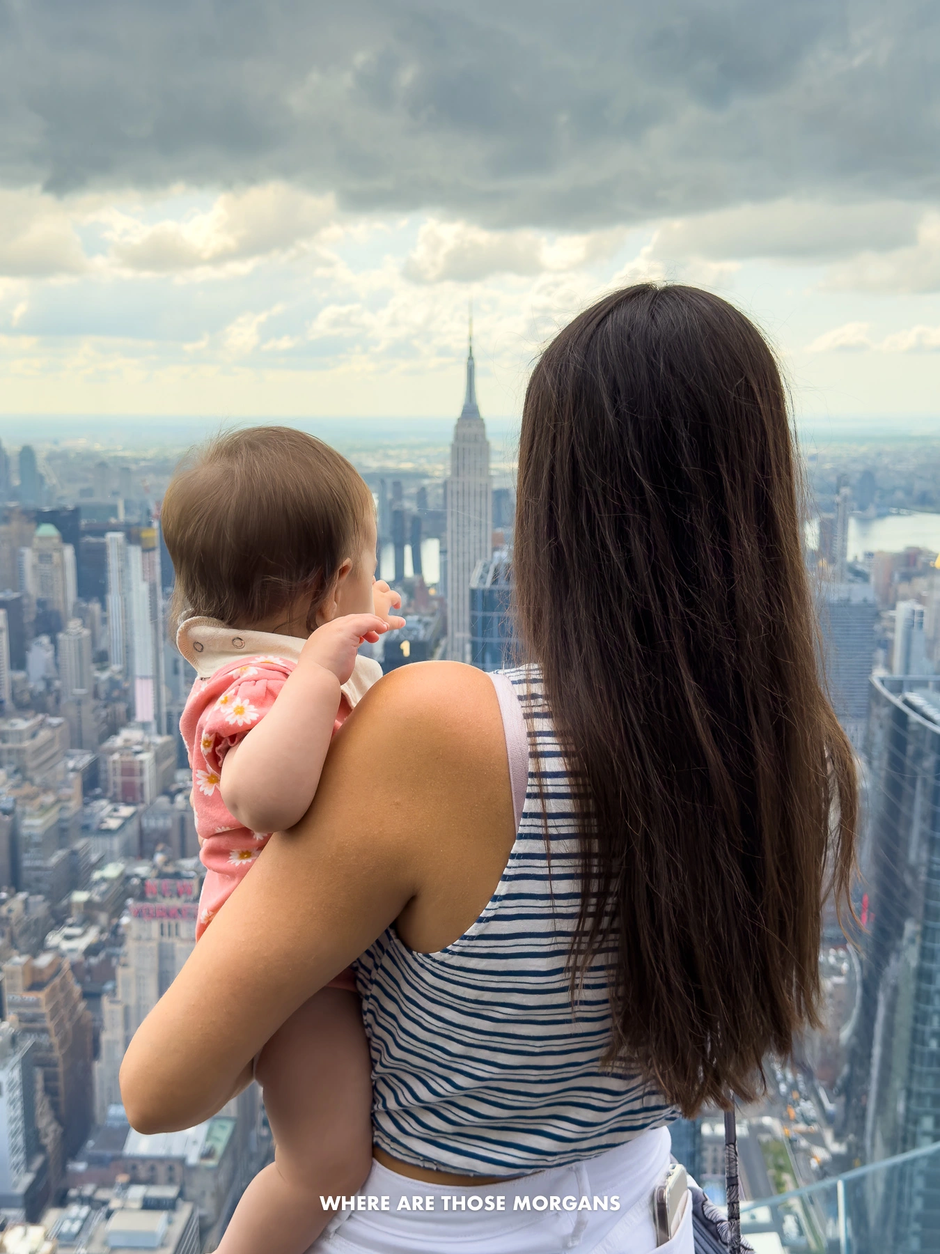 Kristen from Where Are Those Morgans holding her daughter and pointing at the Empire State Building among the NYC skyline