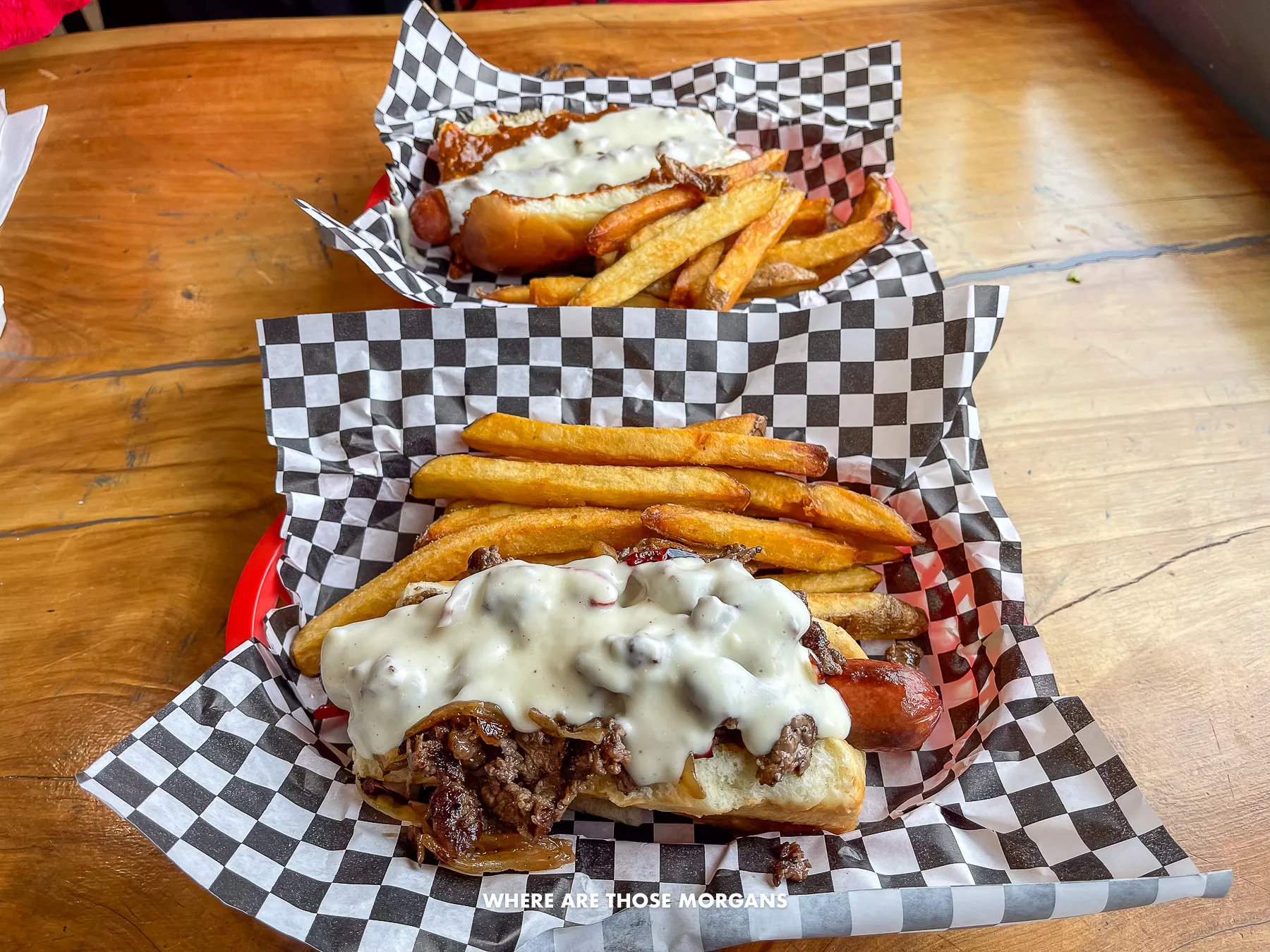 Photo of two hot dogs and fries in baskets on a table