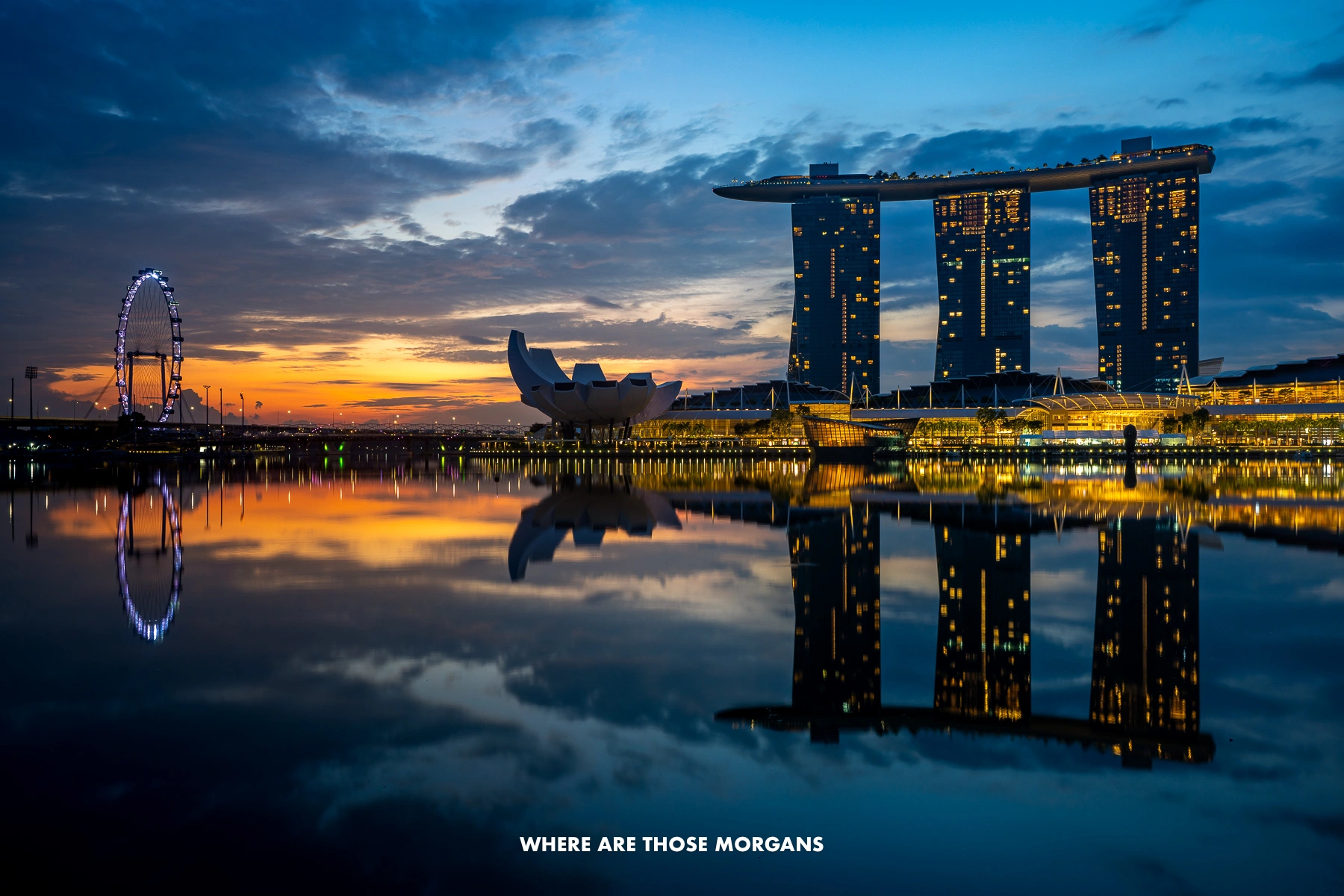 Marina Bay Sands hotel and Singapore Flyer reflecting in the bay at dawn with sunrise colors in the sky