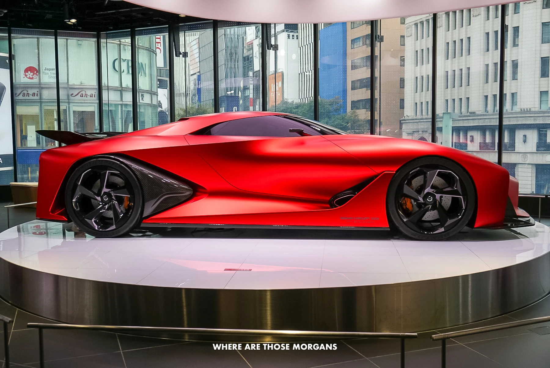Sleek red Nissan concept car on a spinning platform inside a building in Ginza, Tokyo