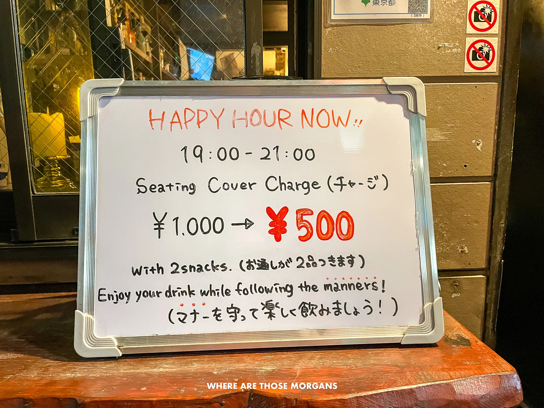 Sign showing happy hour prices on a whiteboard outside a small pub in Shinjuku