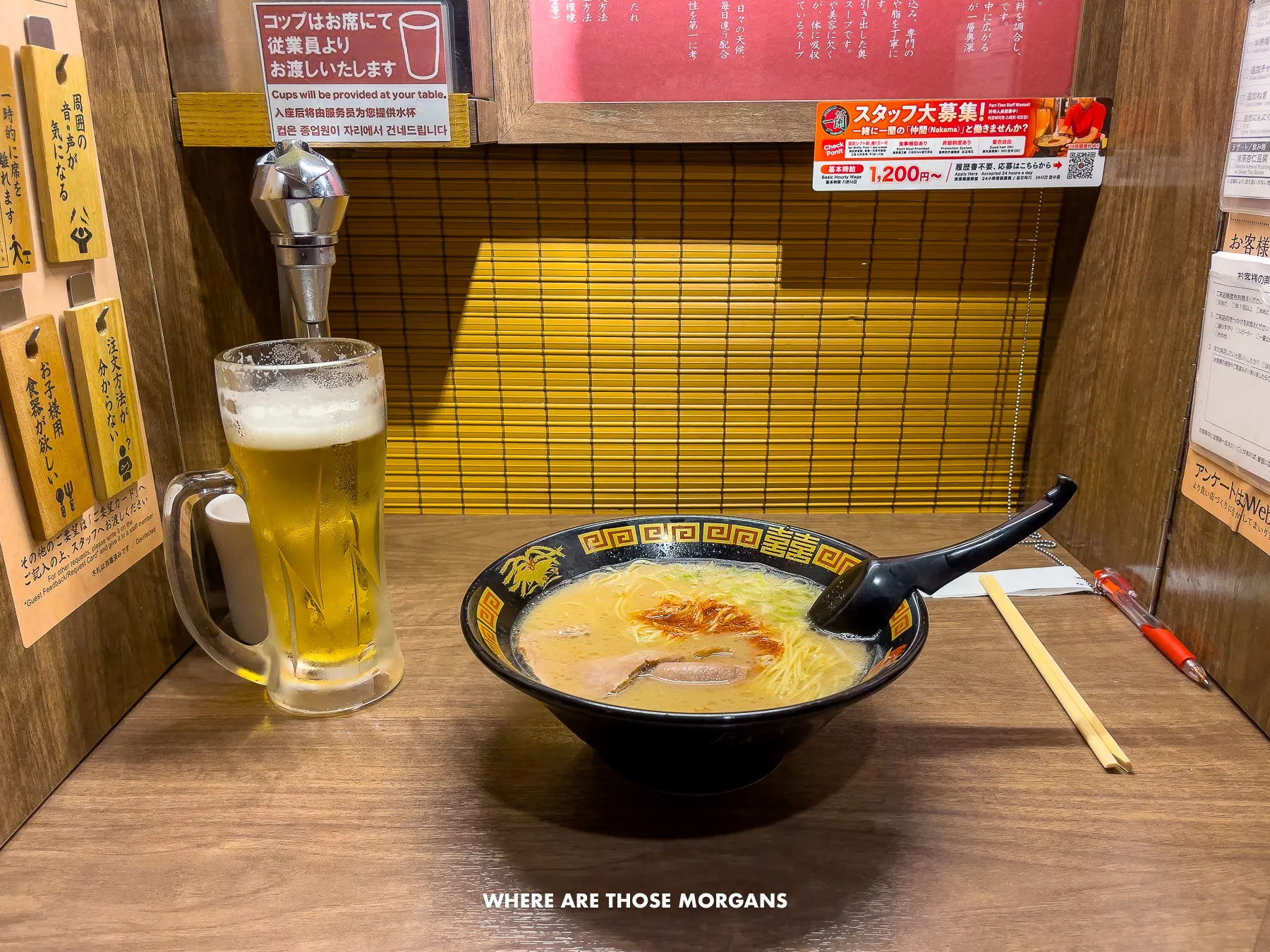 Bowl of ramen and a beer in a small individual cubicle with a window slot at the back to be served