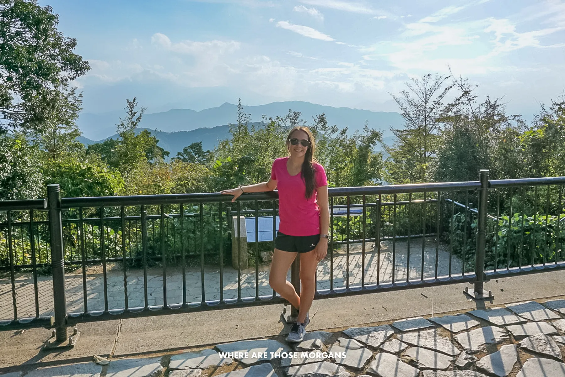 Kristen from Where Are Those Morgans leaning against a railing with views over trees and distant mountains in Japan