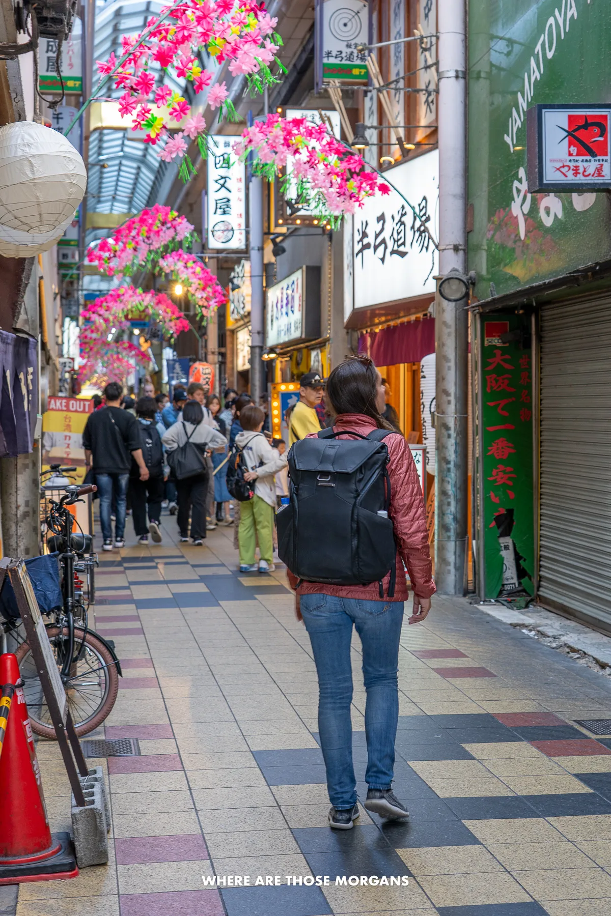Kristen from Where Are Those Morgans walking through a covered shopping arcade with other people in Osaka Japan