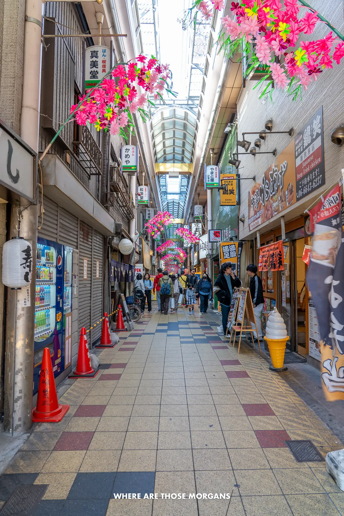 Covered shopping arcade in Japan with people walking through the narrow strip flanked by shops and restaurants