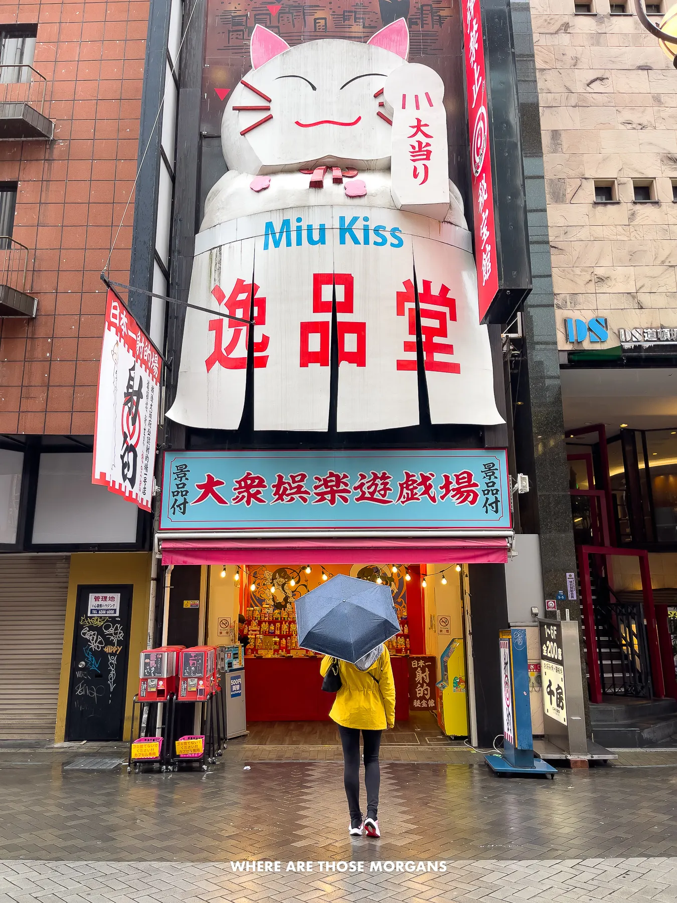Kristen from Where Are Those Morgans standing with an umbrella in front of a building in Japan with a white cat facade