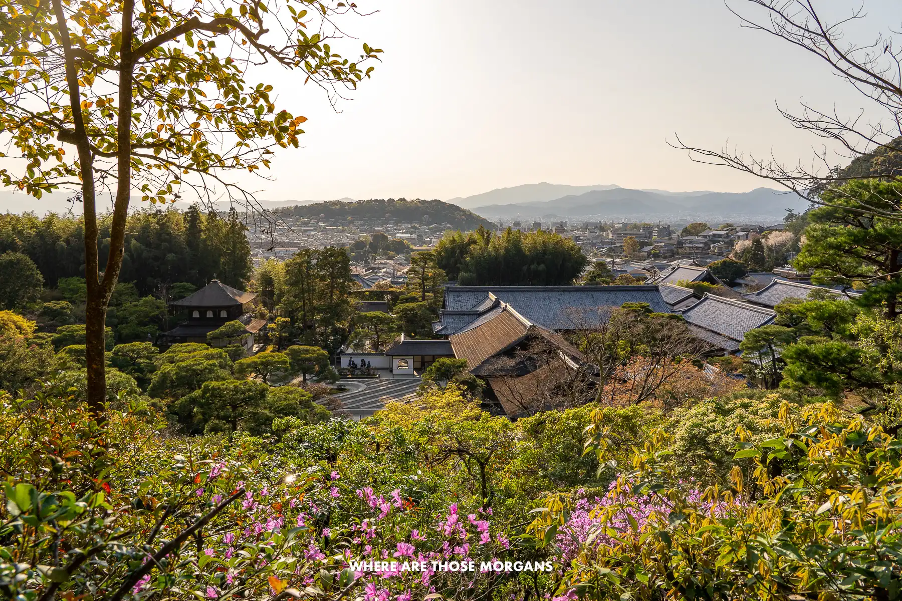 Elevated view over trees, temple, gravel garden and northern Kyoto at sunset from Ginkakuji